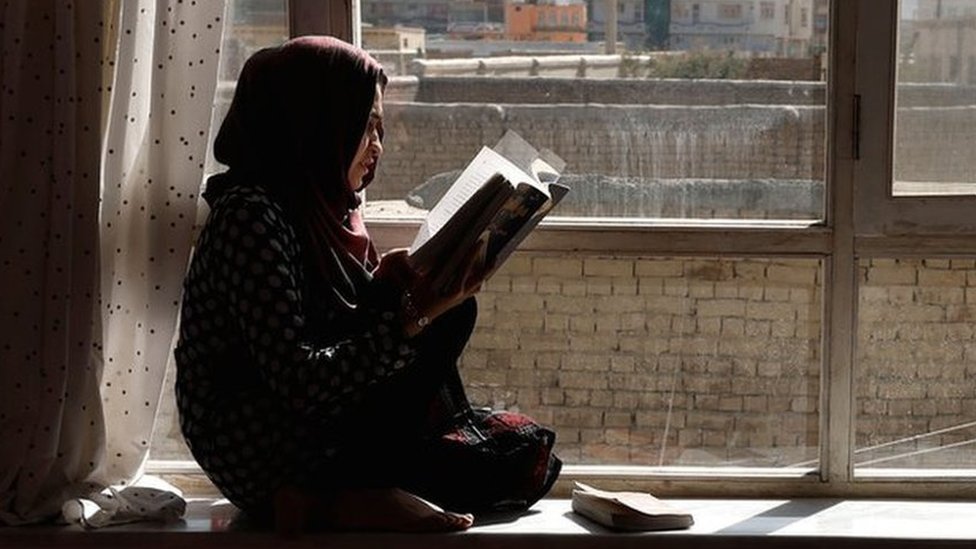 girl reads at her window