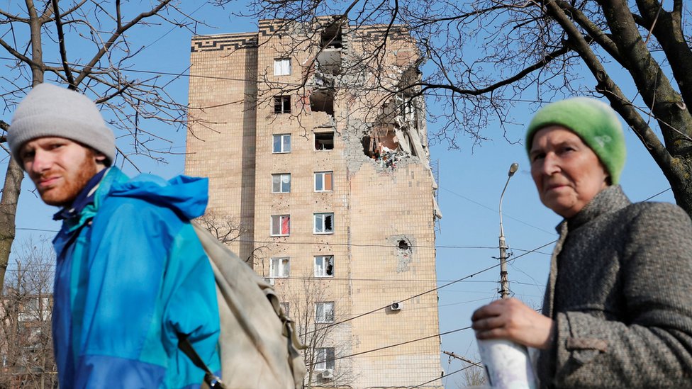 Жители Мариуполя около одного из разрушенных зданий