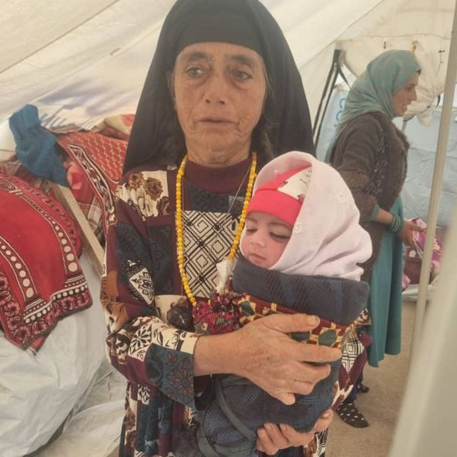 A woman holds a newborn baby in swaddling clothes