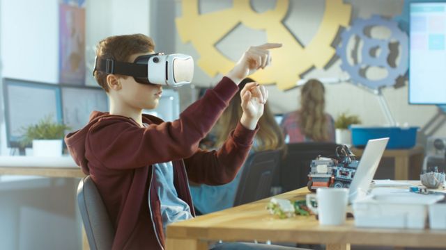 A boy wearing a VR headset in a classroom