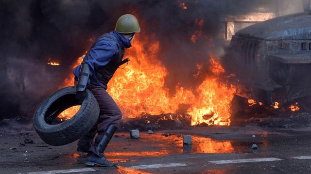 Протестующий швыряет покрышку в огонь