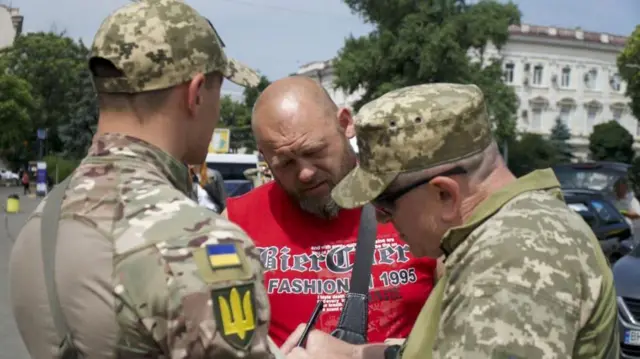 Двое мужчин в военной форме разговаривают с третьим - в штатском