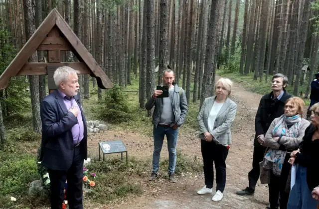 участники акции в Сандармохе у памятного креста в лесу