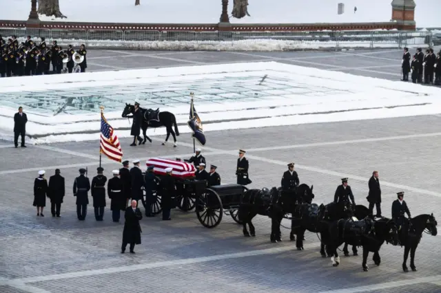 Повозка с лошадьми, везущая завернутый во флаг США гроб в Вашингтоне.