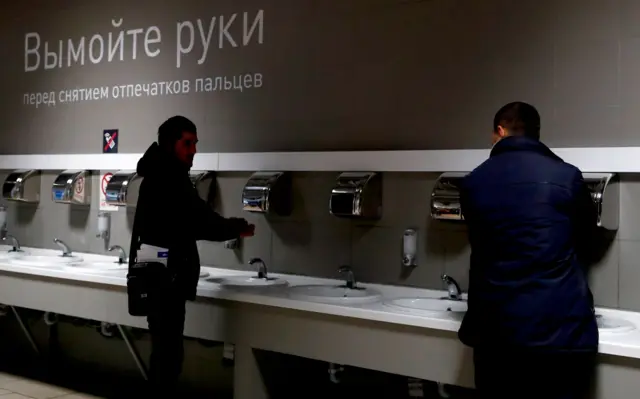 Иностраные граждане моют руки перед дактилоскопической регистрацией на территории Многофункционального миграционного центра
