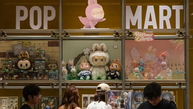 Покупатели осматривают витрину Pop Mart, заполненную персонажами Лабубу и коллекционными фигурками из серии «Монстры», 16 июня 2025 года в Чунцине, Китай.