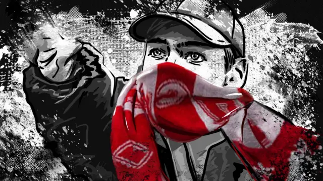 Человек в бейсболке и шарфе футбольного клуба, закрывающем пол-лица, в агрессивной позе