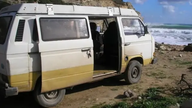 Старый автофоургон с открытой дверцей стоит на берегу моря