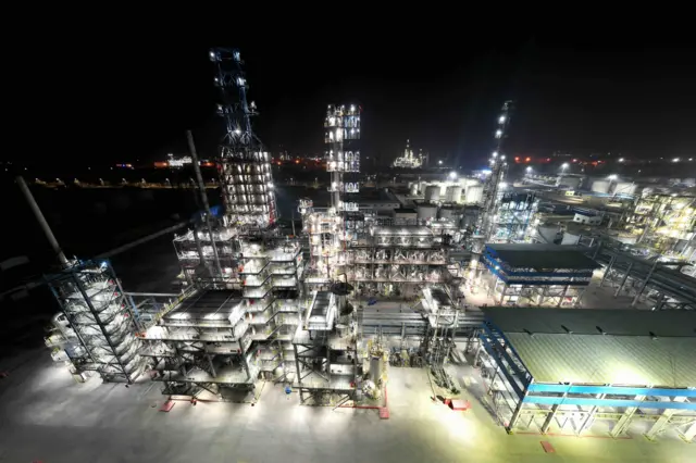 Аэрофотография показывает ярко освещенный нефтеперерабатывающий завод.