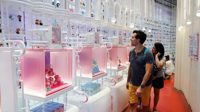 Мужчина и женщина с изумлением смотрят на стену с куклами Pop Mart.