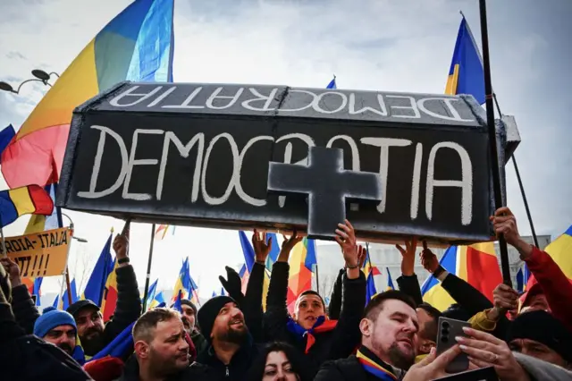 Люди несут гроб с надписью "Демократия" на румынском языке