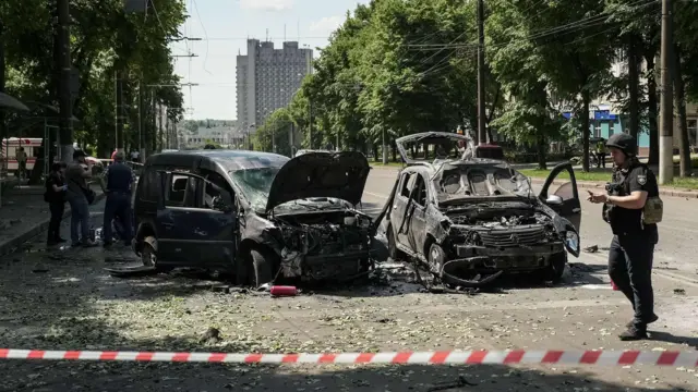 За полицейской лентой стоят две поврежденные при обстреле машины.
