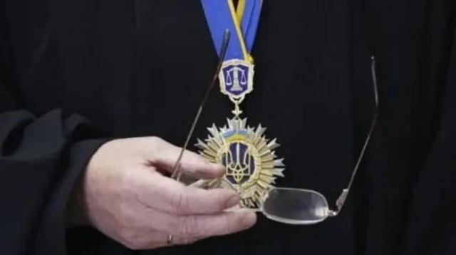 Человек с прокурорской звездой Украины на шее и с очками в руке