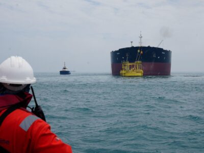 Сотрудник порта смотрит на нефтяной танкер, пришвартованный в море у нефтяного терминала