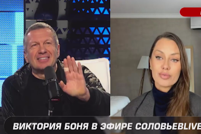 Скриншот из эфира, на одной половине улыбается Владимир Соловьев, поднося руку (на указательном пальце — пластырь) к микрофону, на другой половине Виктория Боня.