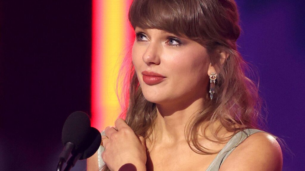 Taylor Swift looks away from camera while speaking into a microphone onstage at the iHeartRadio music awards in LA in March.