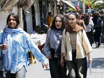 Молодые женщины идут по оживленной торговой улице в Тегеране