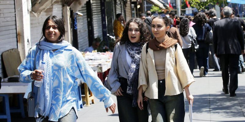 Молодые женщины идут по оживленной торговой улице в Тегеране