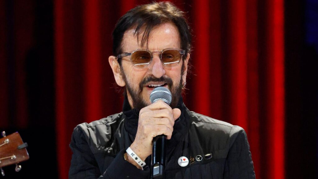 Ringo Starr performs at The Grand Ole Opry on 21 February 2025 in Nashville, Tennessee. He is wearing a black jacket and sunglasses.