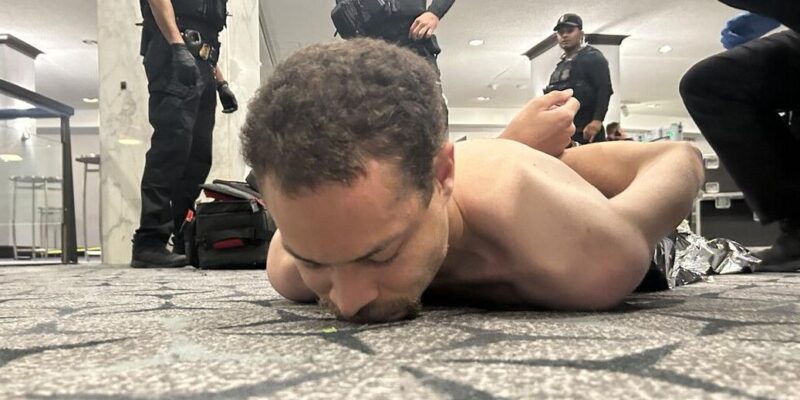 Подозреваемый в стрельбе лежит на полу в отеле Washington Hilton без рубашки и со связанными за спиной руками