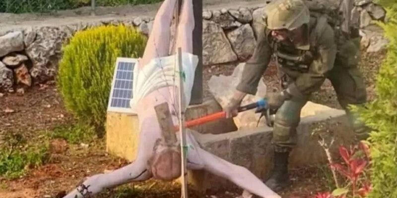 Израильский солдат ударяет кувалдой по голове перевернутой статуи Иисуса Христа на юге Ливана. Фото: апрель 2026 г.