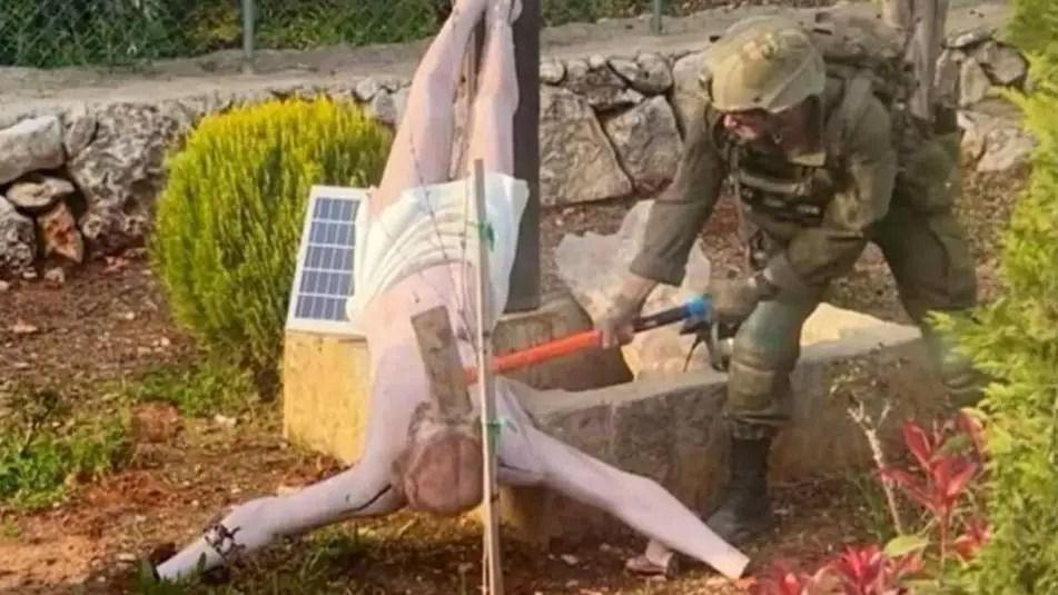 Израильский солдат ударяет кувалдой по голове перевернутой статуи Иисуса Христа на юге Ливана. Фото: апрель 2026 г.