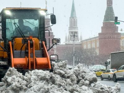 Трактор сгребает кучу снега у стен московского Кремля