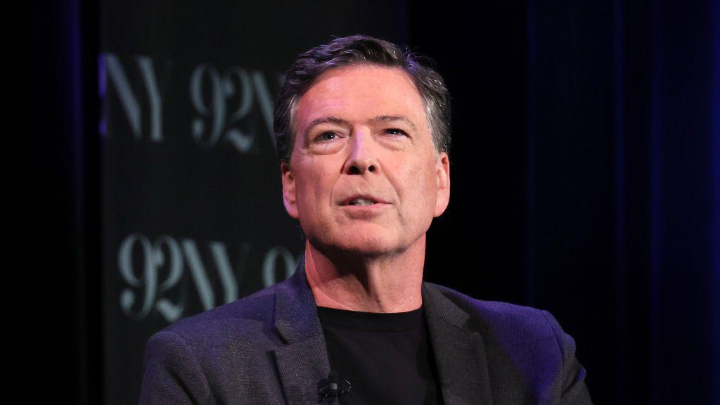 Джеймс Коми в черном пиджаке и черной водолазке с небольшим микрофоном на лацкане.