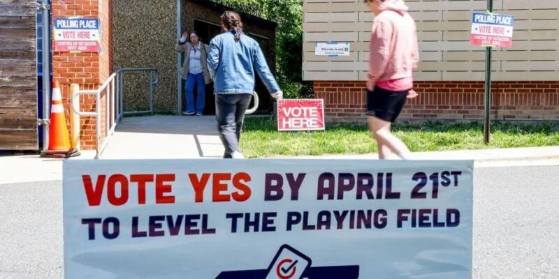 Плакат с надписью «Голосуйте за» у входа в избирательный участок в начальной школе Абингдона во время голосования в Арлингтоне, штат Вирджиния, США, 21 апреля 2026 года.