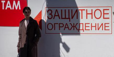 Женщина стоит у надписи на стене "Защитное ограждение" в Белгороде