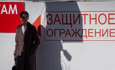 Женщина стоит у надписи на стене "Защитное ограждение" в Белгороде