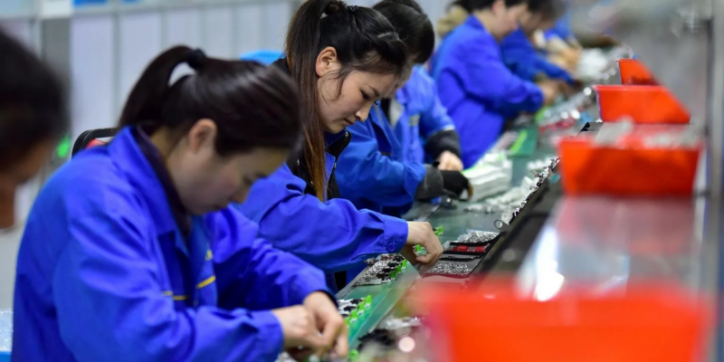 Китайские рабочие - все женщины - в синей спецодежде собирают электронику