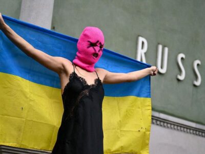 Участница Pussy Riot держит украинский флаг перед павильоном России