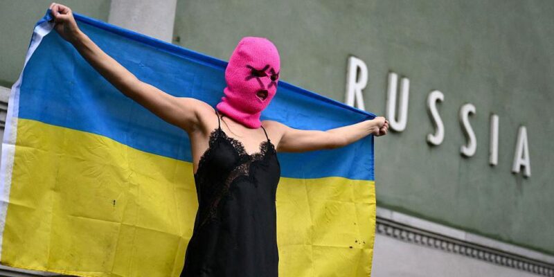 Участница Pussy Riot держит украинский флаг перед павильоном России