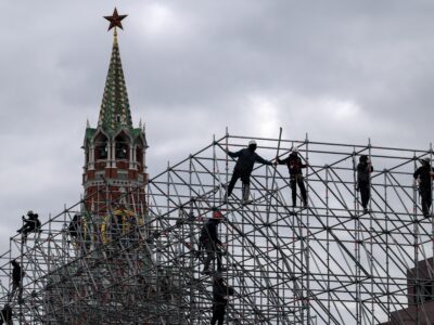 Рабочие монтируют конструкцию сцены на фоне Спасской башни Кремля