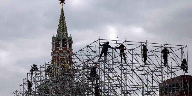 Рабочие монтируют конструкцию сцены на фоне Спасской башни Кремля