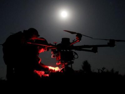 Двое военных готовят к запуску дрон. Ночь, светит луна