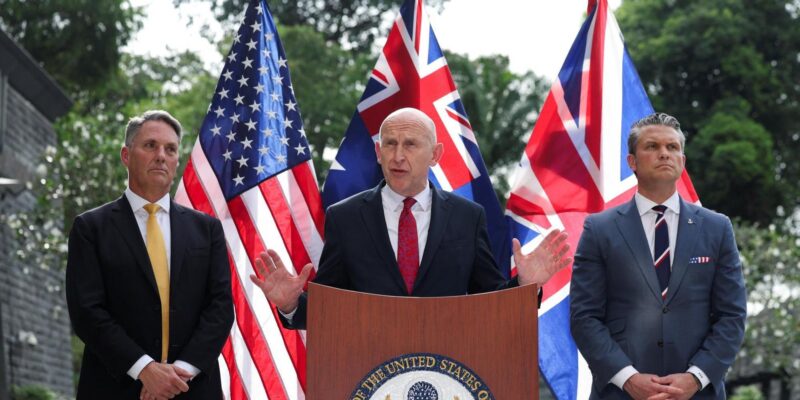 На фоне флагов Австралии, Британии и США слева направо стоят министры обороны этих стран Ричард Марлз, Джон Хили и Пит Хегсет