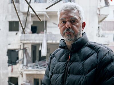 Middle-aged man, Mohammed, in ruins of wrecked apartment block