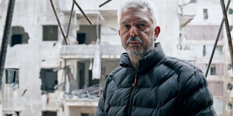 Middle-aged man, Mohammed, in ruins of wrecked apartment block