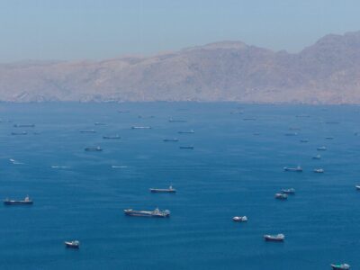 Множество судов на сравнительно небольшом участке моря, вид с дрона. На заднем плане горы
