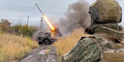 Российский военный (вид со спины) наблюдает за пуском реактивного снаряда из установки «Град»