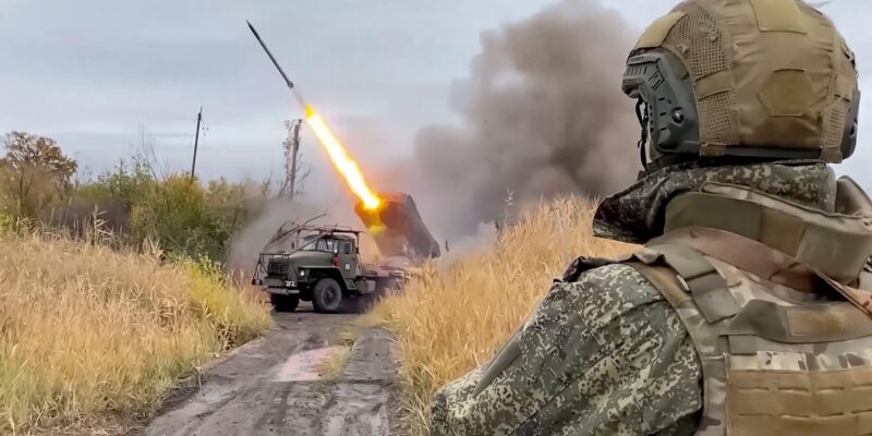 Российский военный (вид со спины) наблюдает за пуском реактивного снаряда из установки «Град»