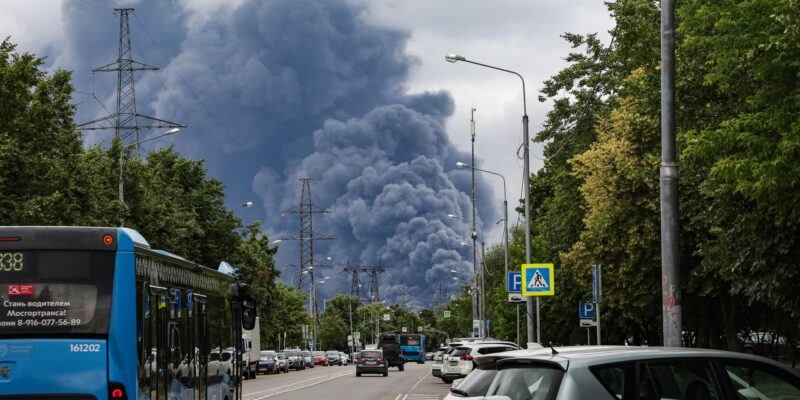 Очереди из десятков автомобилей. Наблюдается ли в Москве дефицит бензина? 1 Клубы дыма над Москвой после атак ВСУ 18 июня на фоне проезжей части, на которой видны припаркованные и едущие по дороге автомобили и автобусы