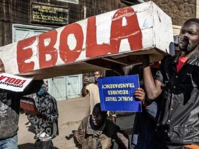 В Кении полиция снова разогнала акцию протеста против планов США построить карантинный центр для больных Эболой американцев 2 Протестующие несут белый гроб из картона, на боку которого красной краской написано слово «Эбола», и плакаты с надписями на суахили «Мы против Эболы» и на английском языке «Доверие общества требует прозрачности».