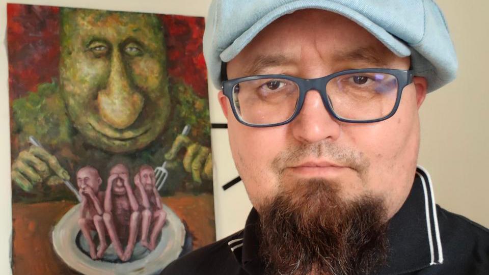 «Давал столько поводов, за которые сейчас убивают людей». Чем известен художник Скрепецкий, застреленный в Польше 1 Семен Скрепецкий на фоне своей работы, на которой изображен Путин
