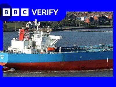 Танкер Forwarder стоит на якоре в порту. На изображении судно наложено на фоне фирменных цветов и логотипа BBC Verify.