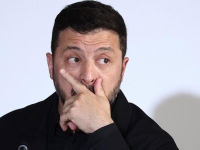 Владимир Зеленский задумчиво смотрит вбок, прикрыв ладонью рот