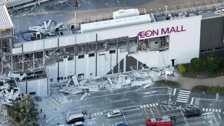 Вид с высоты птичьего полета на торговый центр Aeon Mall с разбитыми окнами и обломками на парковке