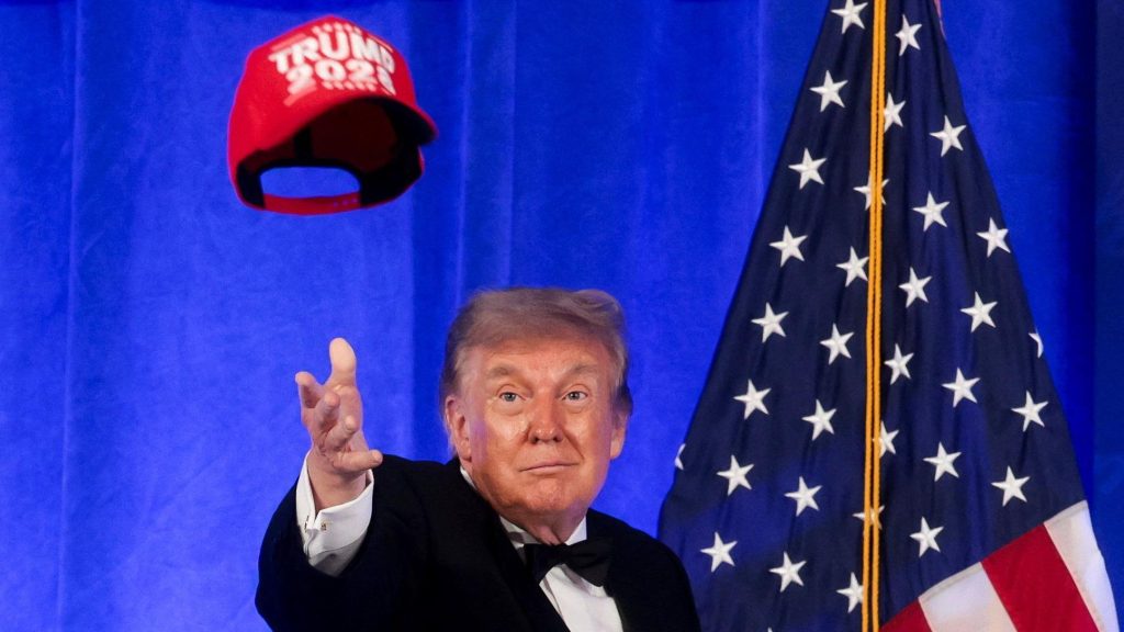 Трамп, кидающий в воздух красную кепку с надписью Trump 2028, за ним — флаг США.